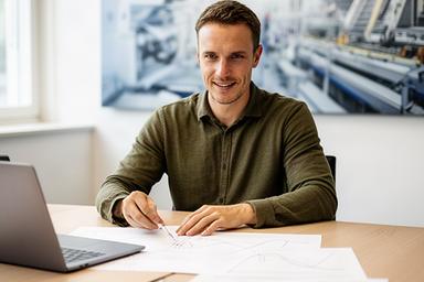 Data-Science-Berater an einem Tisch mit Prognosekurven und Produktionsdaten aus einem Schweizer Unternehmen